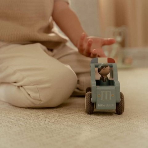 Dziecko bawiace sie drewnianym samochodem policjnym Little Dutch z policjantem w srodku