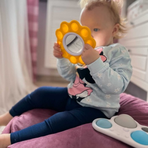 Dimpl Słoneczko i Chmurka Fat Brain Toy Co Bąbelki  w rękach dziecka