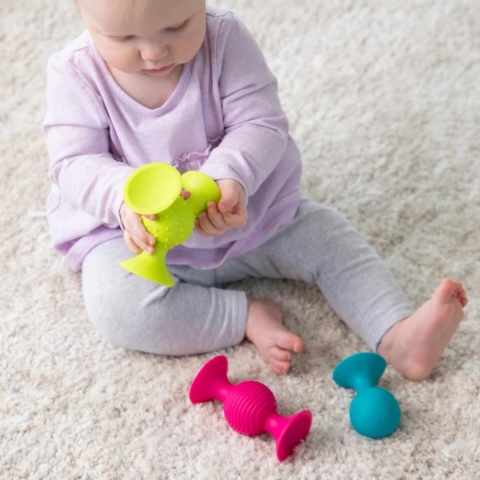 Przyssawki z grzechotką Fat Brain Toy Co. w rękach dziecka