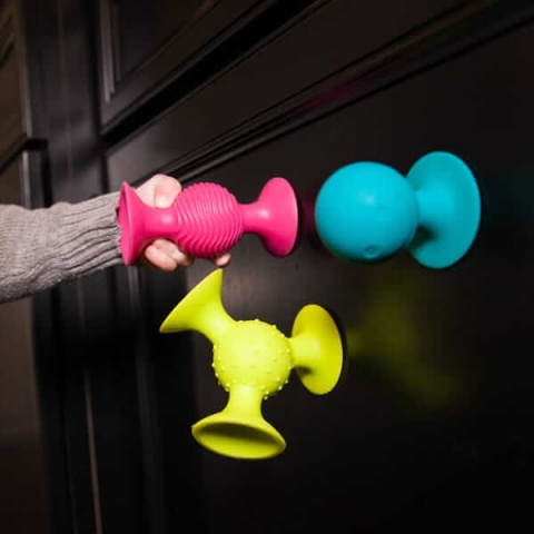 Przyssawki z grzechotką Fat Brain Toy Co. przyczepione na lodówke