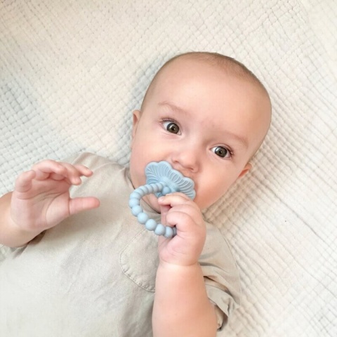 Czarny gryzak silikonowy RaZbaby z uchwytem malina w rękach dziecka